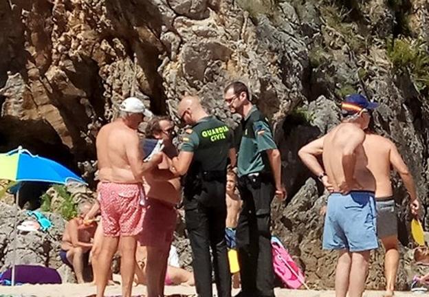 Agentes de la Guardia Civil conversan con el bañista que el lunes increpó a un socorrista en Borizu.
