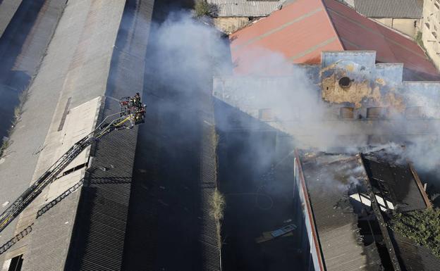 Los bomberos, trabajando en la nave afectada por el fuego./Peteiro