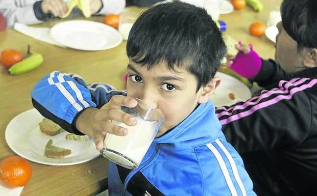 Unos niños toman leche y fruta en un comedor escolar. /M. ROJAS