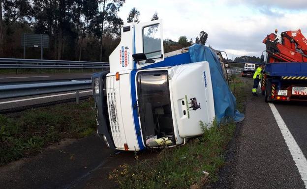 El camión volcado en la calzada con la grúa que iba a retirarlo. /lva