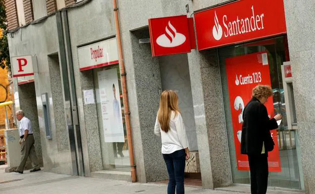 Una mujer saca dinero del cajero automático de una oficina del Banco Santander en Barcelona. /Albert Gea (Reuters)