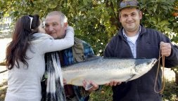 Sandra, hija de Gonzalo Álvarez, felicita a su padre tras capturar el campanu. Junto a ellos, Hugo, sobrino del pescador./ EFE/