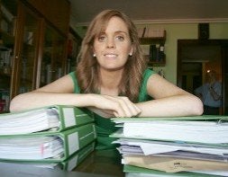 Sara López sonríe apoyada sobre sus apuntes ante la atenta mirada de su padre, al fondo. / L. SEVILLA/
