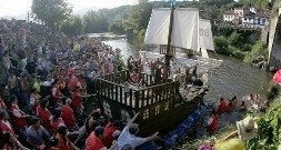 El público ayuda a los participantes de una de las carrozas a trasladar su embarcación al río./ J. C. ROMÁN/