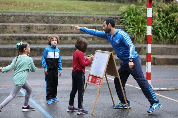 Alejandro Carriedo dirige una actividad en la que los niños de Primaria del colegio Villalegre, en Avilés, calculan restas en el patio. / MARIETA
