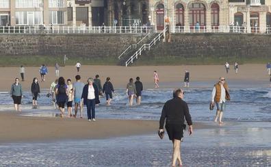 Numerosos gijoneses aprovecharon para mojarse los pies al tiempo que paseaban por San Lorenzo./DAMIÁN ARIENZA