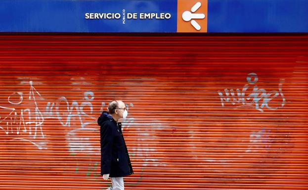 Un hombre con mascarilla pasa frente a una oficina del Servicio Público de Empleo en Oviedo./EFE