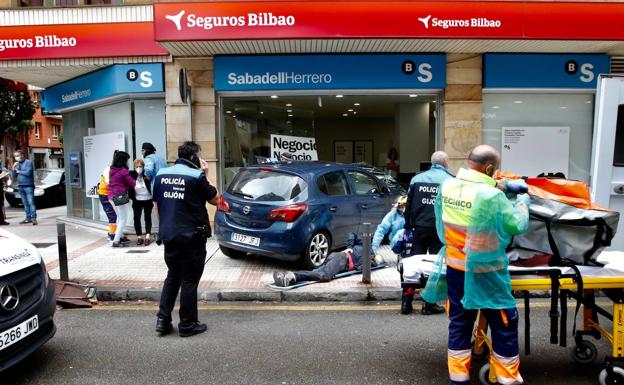 Arrolla a dos paseantes y se empotra contra una sucursal bancaria en Gijón