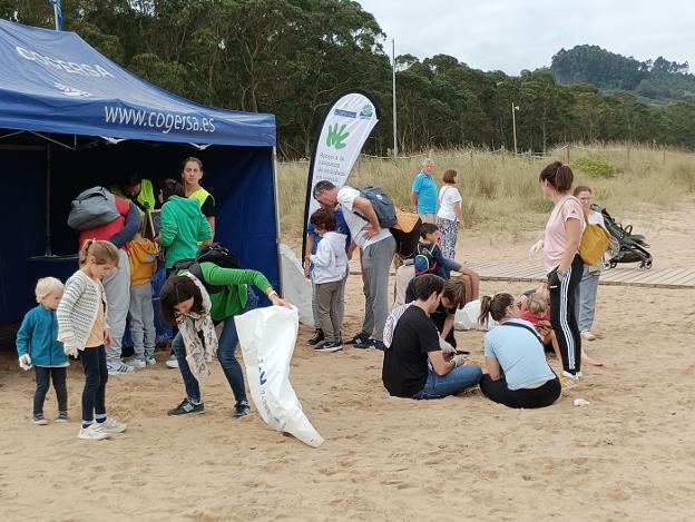 Un centenar de personas se unen para limpiar la playa de Rodiles de basura y residuos